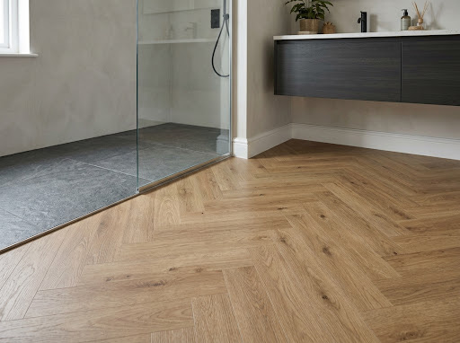 Visgraat PVC-vloer in houtlook naast een inloopdouche met glazen wand