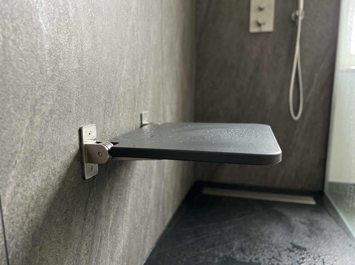 Opklapbaar douchezitje aan een wandpaneel in een inloopdouche